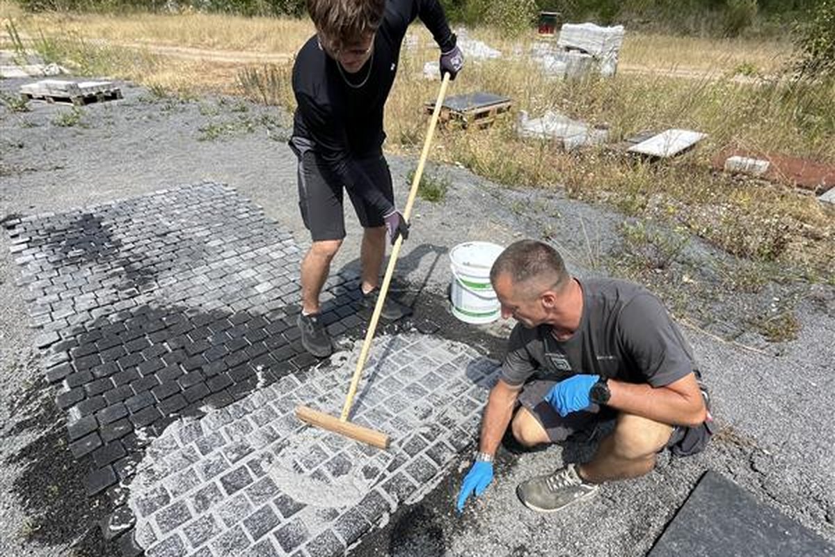 Manuel Alberg et un collègue du service technique d’application de la GftK balaient du mortier de jointoiement sur une surface pavée.